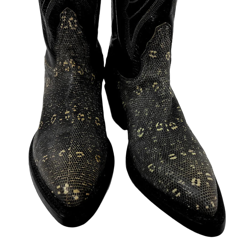 A pair of black cowboy boots with a textured python-patterned shaft and toe caps, featuring small beige leopard-like spots, shown against a plain light gray background.