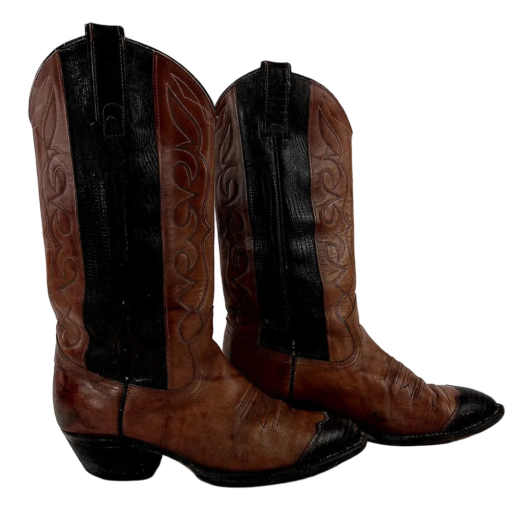 A pair of brown leather cowboy boots with black shaft panels and black toe caps, shown against a plain light gray background.
