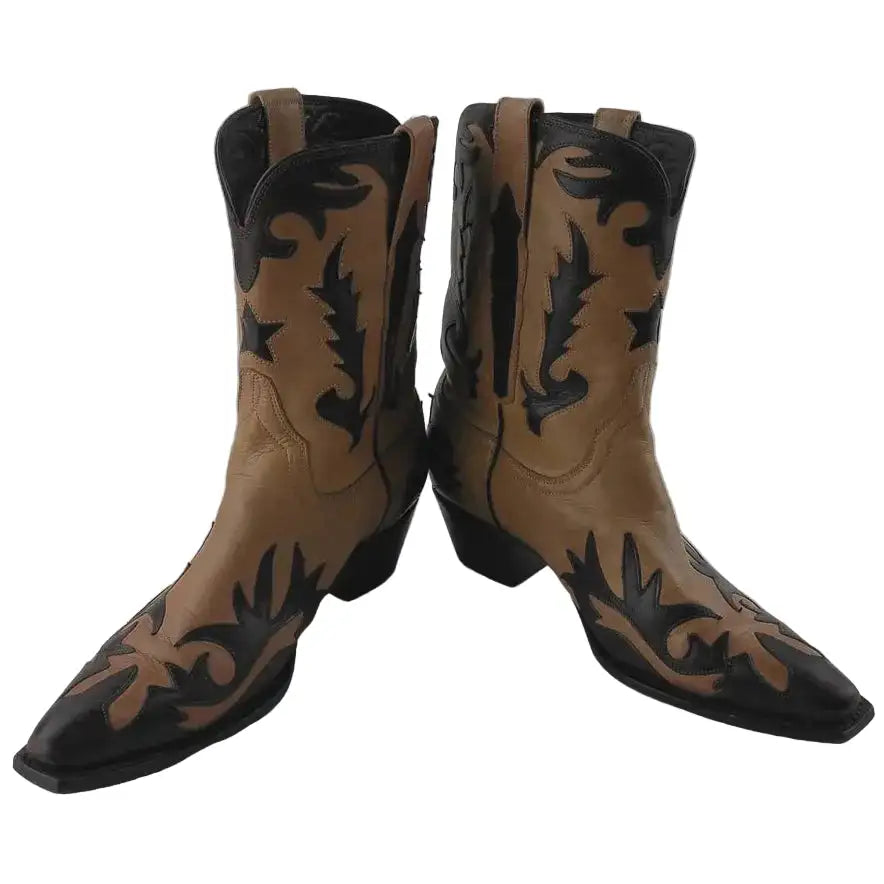 A pair of pointed-toe western cowboy boots in tan and black leather, featuring hand-tooled floral and scrollwork designs on the shafts, photographed against a neutral gray background.