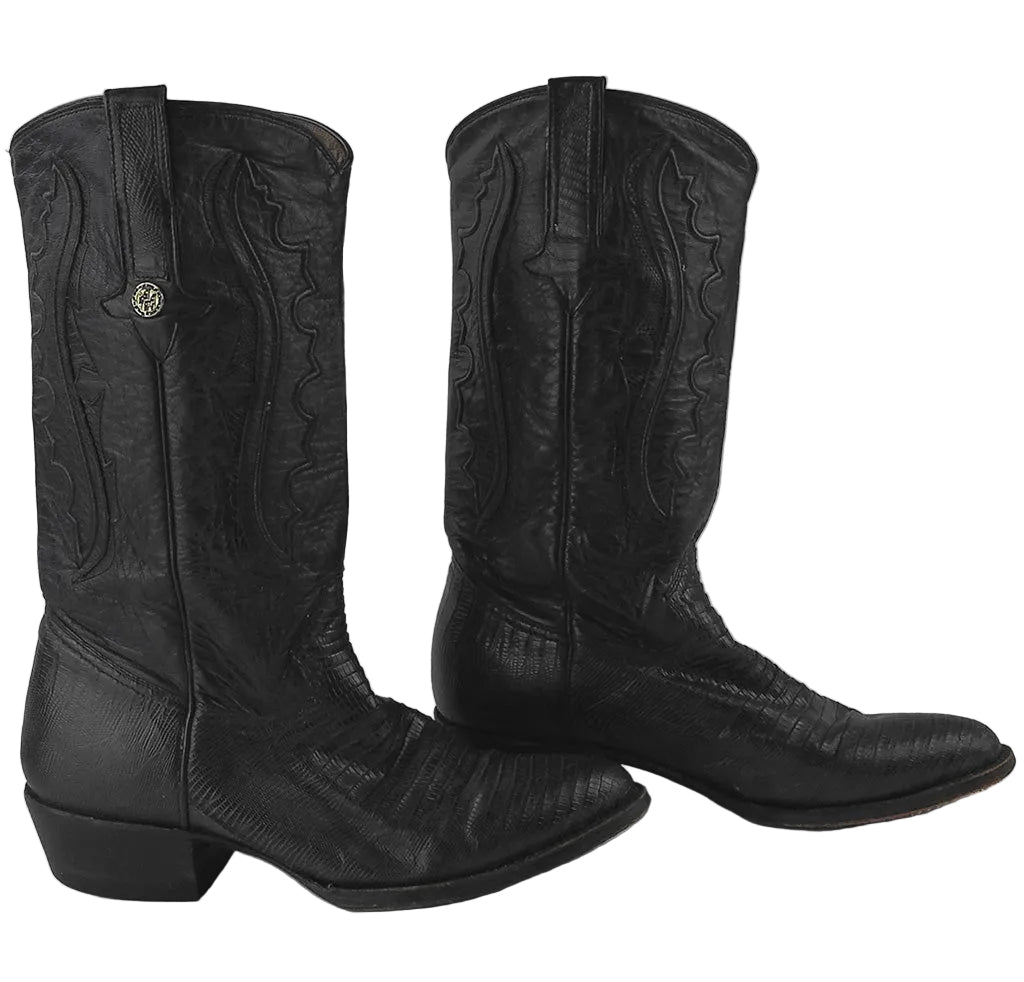 A pair of black leather cowboy boots with western-style stitching and a small gold-tone concho detail, shown against a neutral gray background.