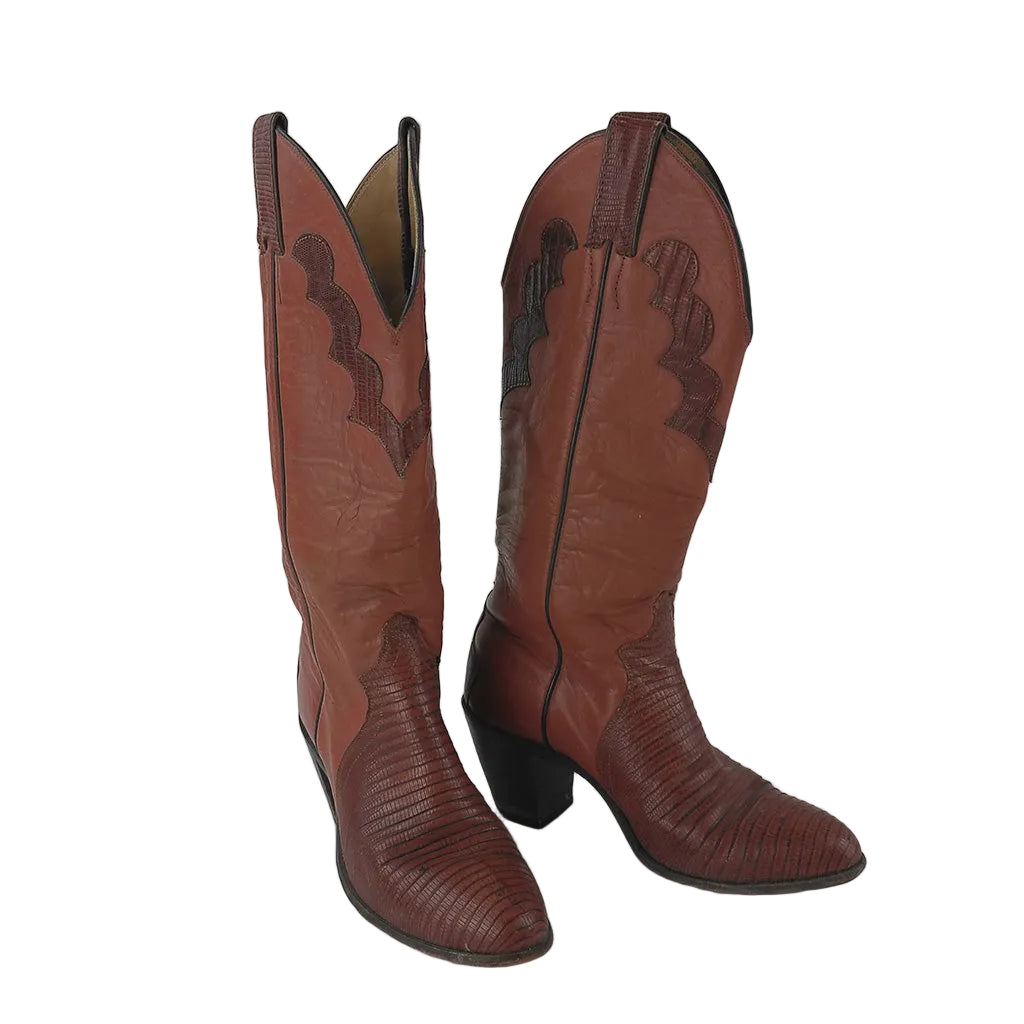 A pair of tall western cowboy boots in reddish-brown leather with textured lizard toes and dark brown stitched detailing, photographed against a neutral gray background.