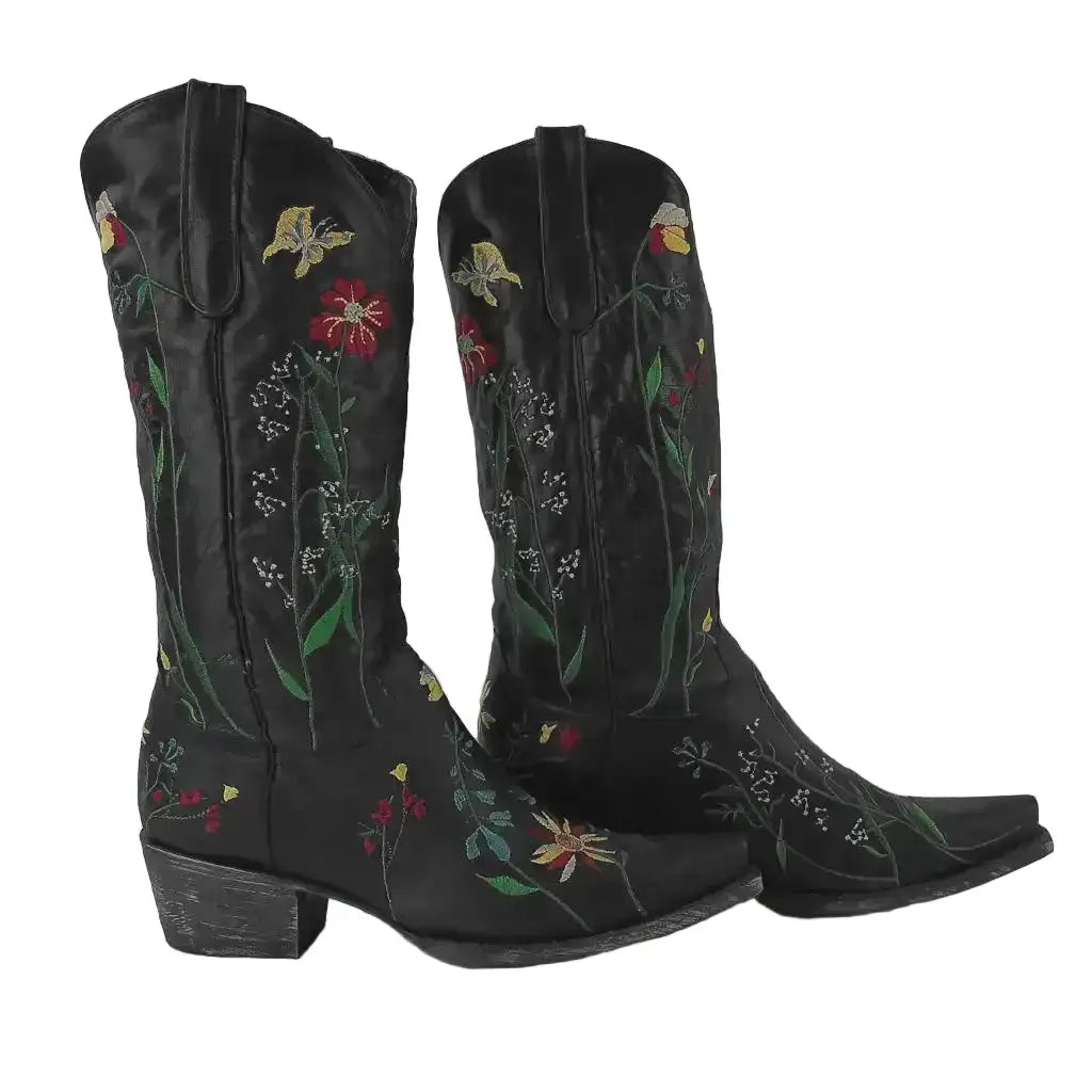 Pair of black cowboy boots with floral embroidery on a gray background