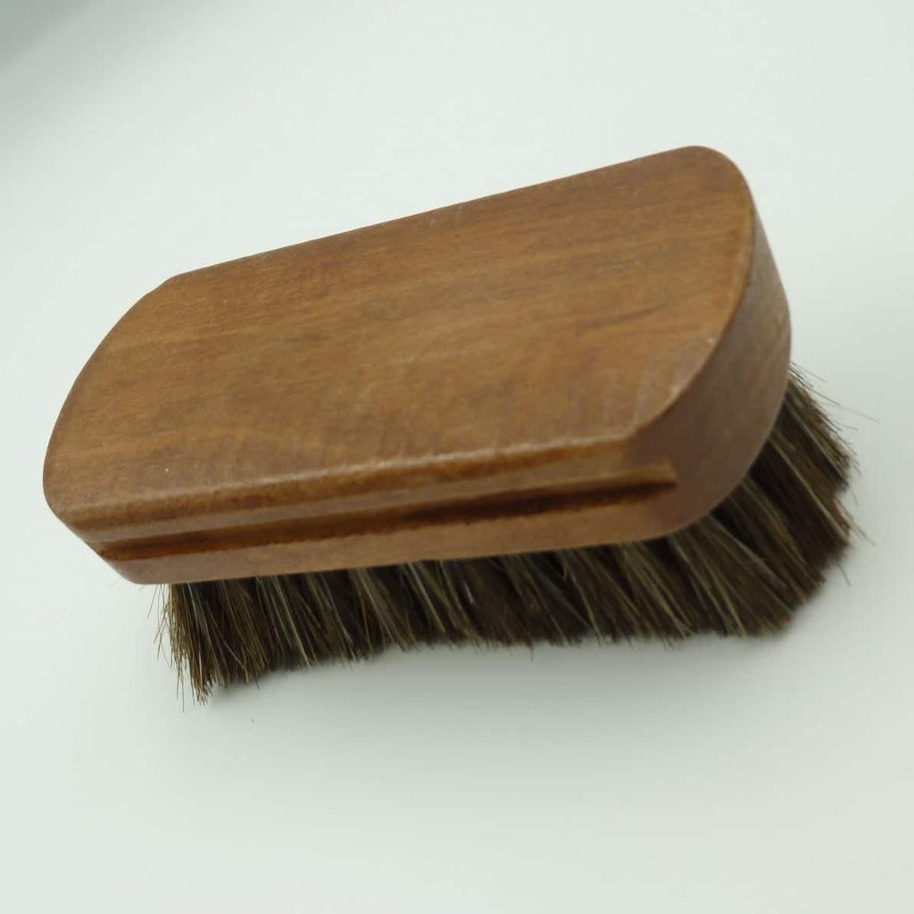 A wooden-handled brush with dark brown horsehair bristles, photographed on a plain white background.