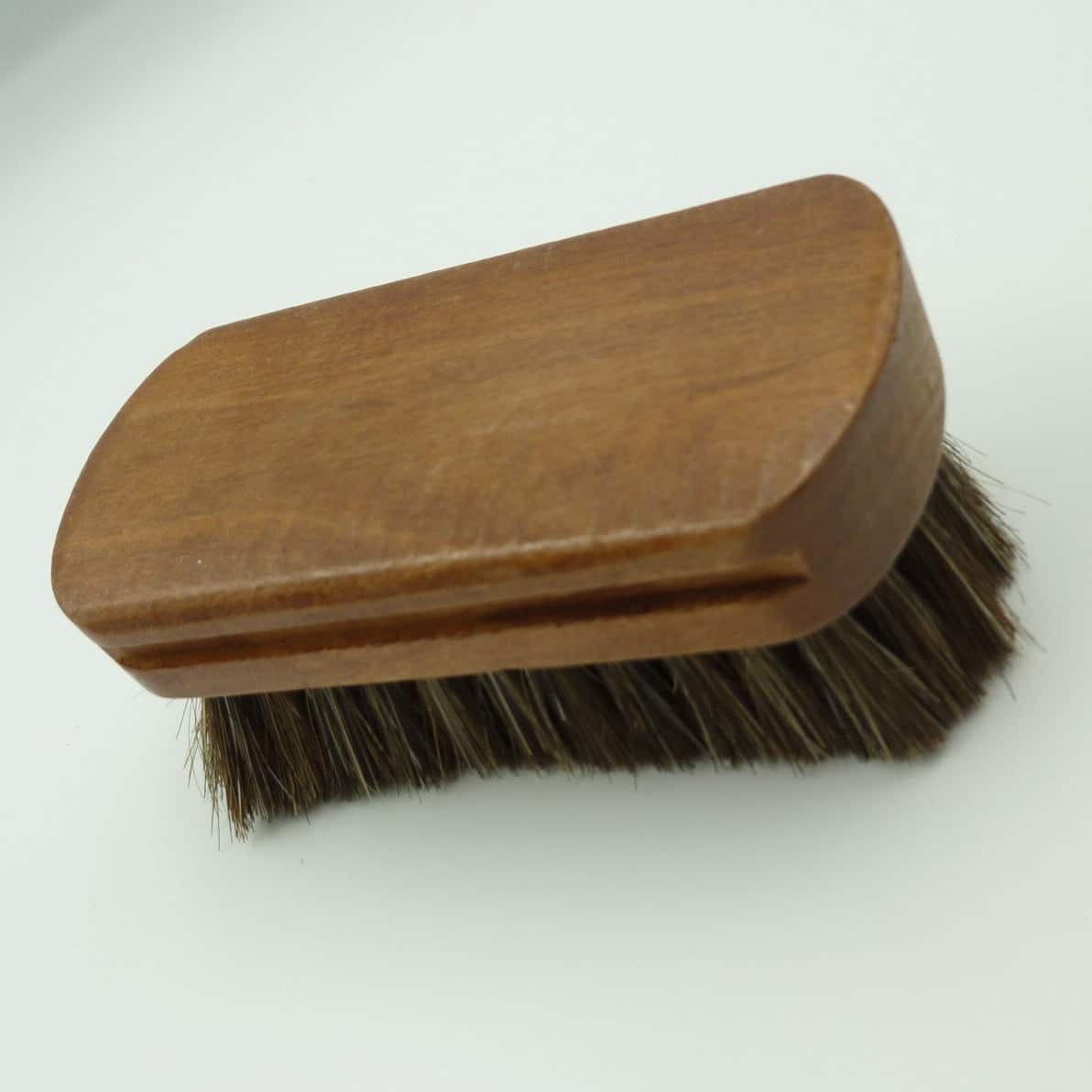 A wooden-handled brush with dark brown horsehair bristles, photographed on a plain white background.