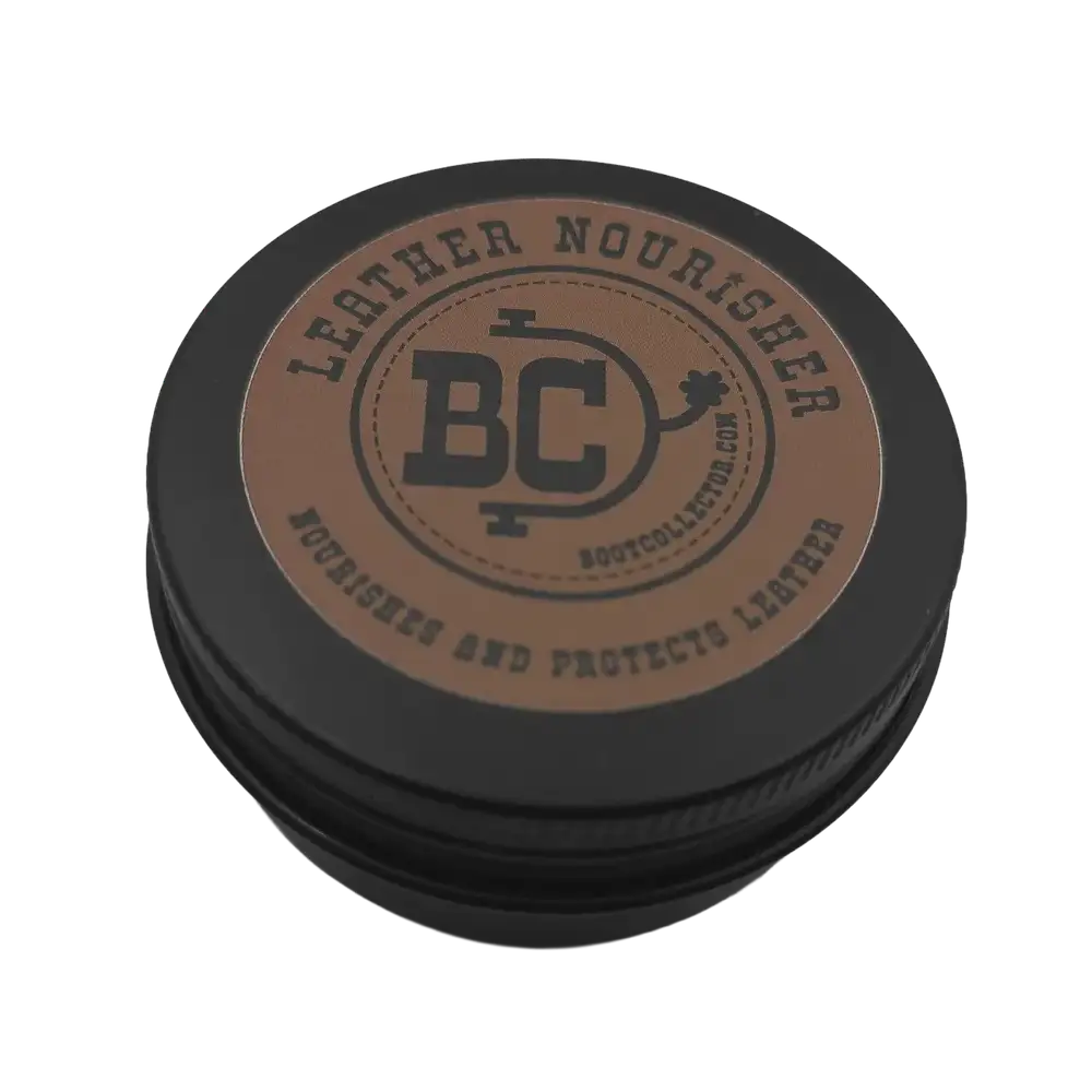 A round black metal tin with a brown circular label on top, photographed on a plain white background. The label reads 'LEATHER NOURISHER' and shows a central 'BC' logo with 'Bootcollector.com' beneath it.